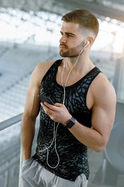 Чоловік слухає музику на телефоні під час вправи на відкритому повітрі . — стокове фото