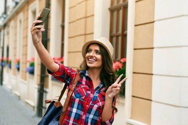 Telefonu açık havada çekim güzel turist kadın.