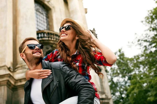 Pareja enamorada. Hombre cargando chica en su espalda en la calle . — Foto de Stock