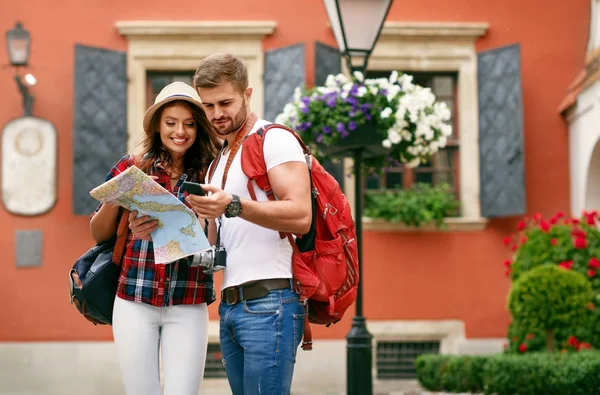 Hermosa pareja de turistas que viajan utilizando el mapa y el teléfono. — Foto de Stock