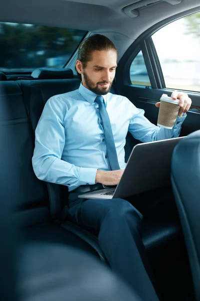 Człowiek pracy na notebooku i picia kawy w samochodzie. — Zdjęcie stockowe