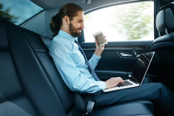 Man Working On Notebook And Drinking Coffee in Car.