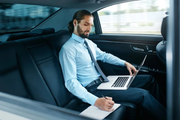 Ritratto di uomo d'affari che lavora su taccuino, viaggiando in auto . — Foto Stock