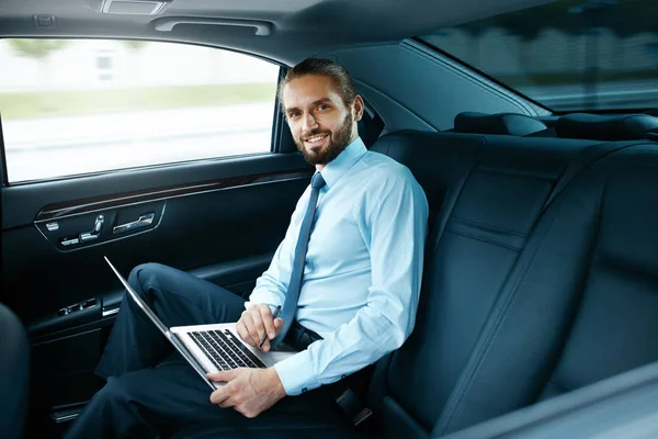 Portrait d'un homme d'affaires travaillant sur un ordinateur portable, voyageant en voiture . — Photo