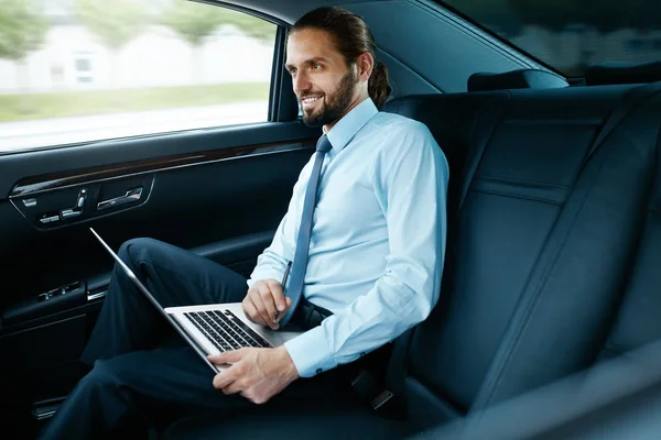 Portrait d'un homme d'affaires travaillant sur un ordinateur portable, voyageant en voiture . — Photo