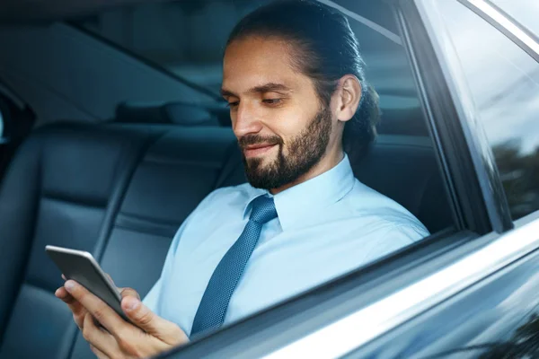 Jeune homme réussi travaillant sur le téléphone assis dans la voiture . — Photo