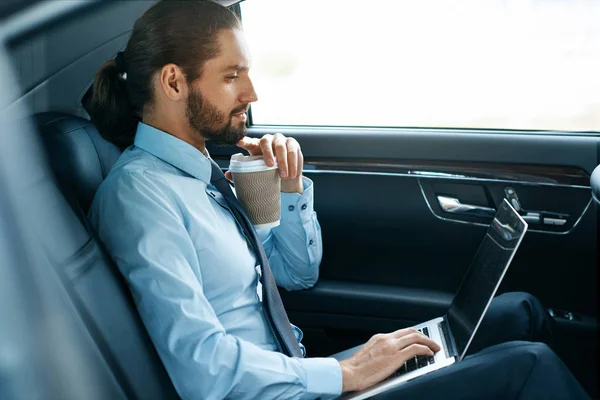 Homme travaillant sur ordinateur portable et boire du café dans la voiture . — Photo