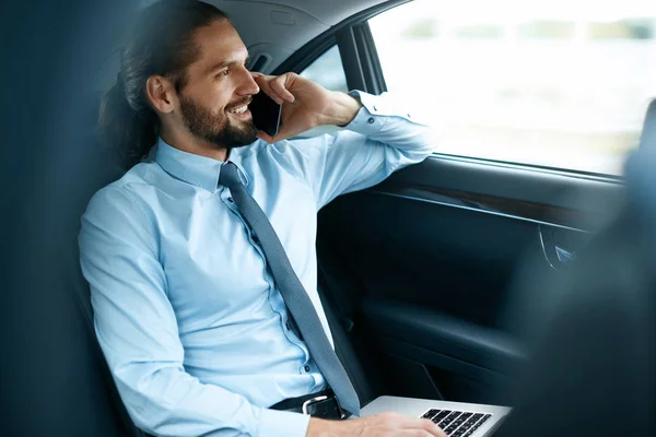 Деловой человек в машине звонит по телефону во время поездки на работу — стоковое фото