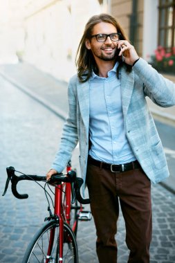 Adam sokakta yürürken telefonla aramayı bisiklet ile.