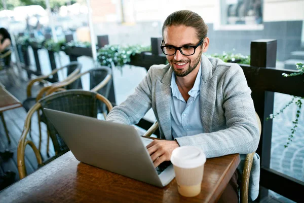 Людина працює на ноутбуці з кафе на відкритому повітрі — стокове фото