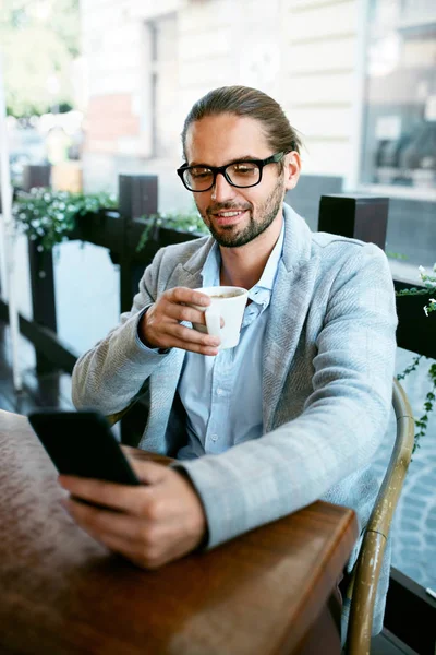 Man With Phone Drinking Coffee In Cafe