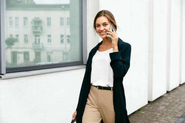 Профессиональная женщина разговаривает по телефону во время прогулки по улице . — стоковое фото