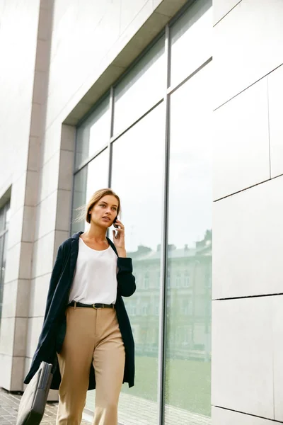 Profesionální žena mluví o telefonu při chůzi kolem ulice. — Stock fotografie