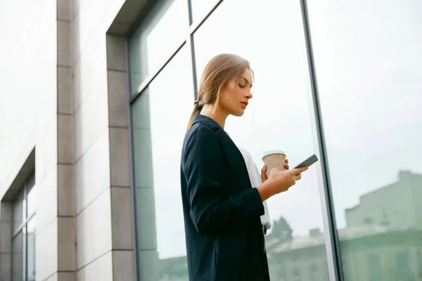 Snygg kvinna med telefon och dricka kaffe utomhus. — Stockfoto