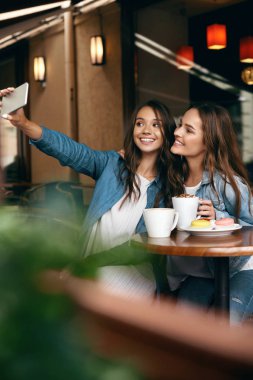 Cafe toplantı kadınlar. Telefonda fotoğrafta arkadaşlar.