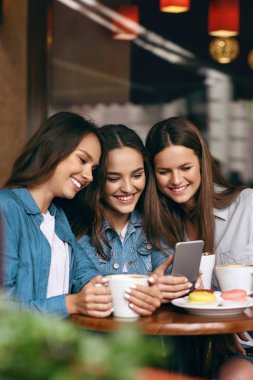 Telefon kullanarak ve Cafe kahve içme genç arkadaşlar.