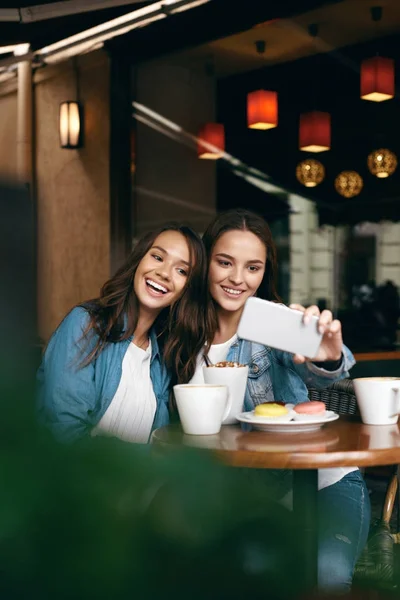 カフェで会う女性。携帯電話で写真を撮る友人. — ストック写真