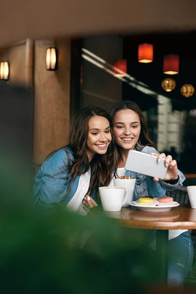 Жінки зустрічаються в кафе. Друзі фотографуються на телефоні . — стокове фото