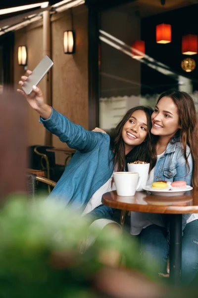 Frauen treffen sich im Café. Freunde fotografieren am Telefon. — Stockfoto