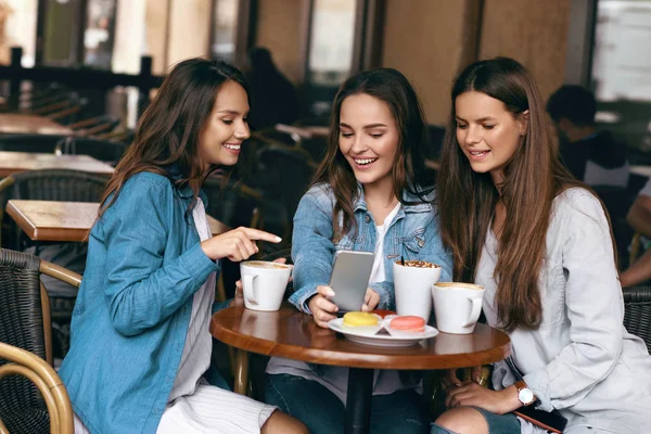 Νεαρό θηλυκό φίλους χρησιμοποιώντας το τηλέφωνο και να πίνει καφέ στο Cafe. — Φωτογραφία Αρχείου