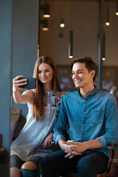 Pár v Cafe. Mladý pár fotografií v telefonu. — Stock fotografie