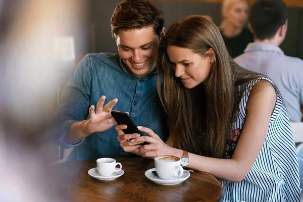 Pareja feliz usando el teléfono, sentado en el café . — Foto de Stock