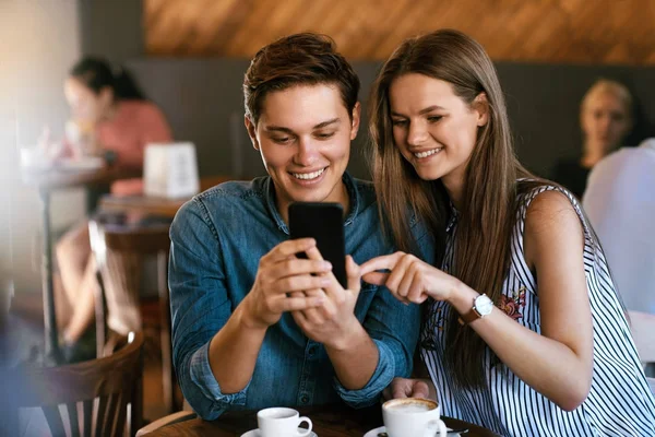 Pareja feliz usando el teléfono, sentado en el café . — Foto de Stock