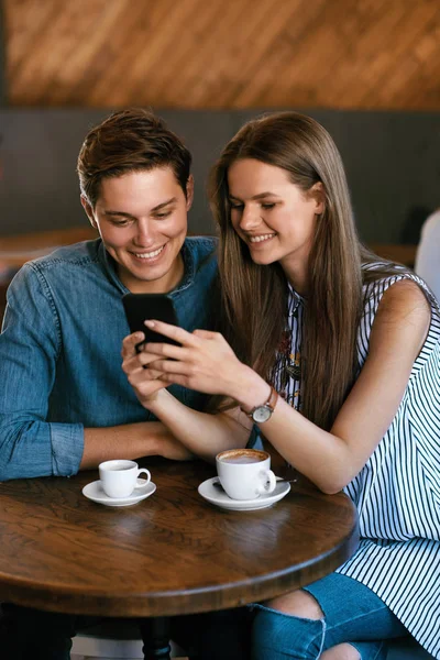 Casal feliz usando telefone, sentado no café . — Fotografia de Stock