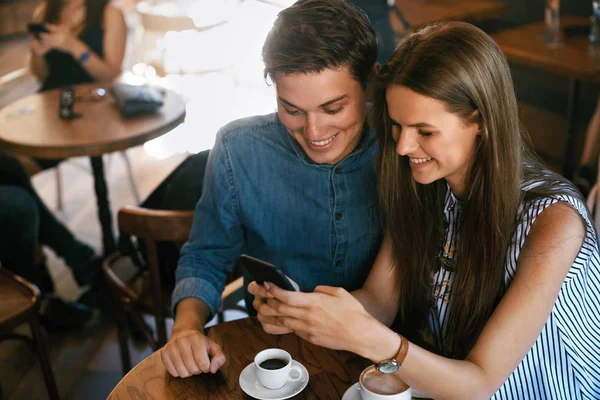 Pareja feliz usando el teléfono, sentado en el café . — Foto de Stock