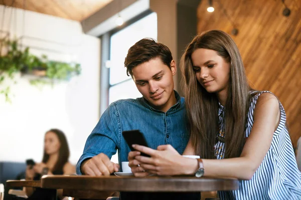 Paar benutzt Telefon während es im Café sitzt. — Stockfoto