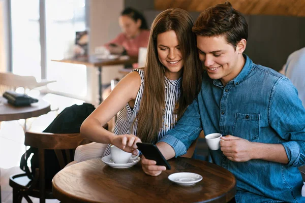 Gelukkige paar met behulp van telefoon, zitten In het Cafe. — Stockfoto