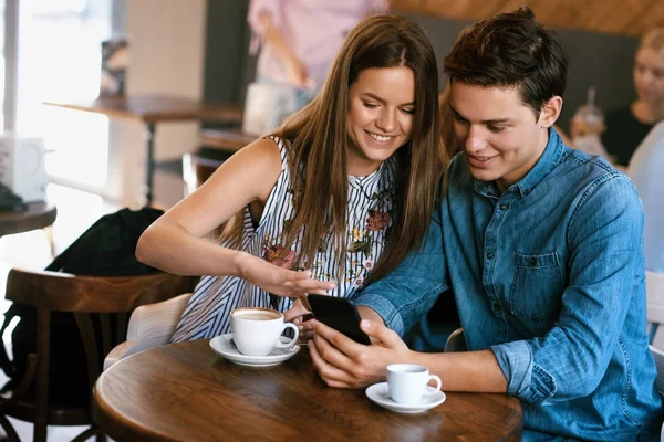 Pareja feliz usando el teléfono, sentado en el café . — Foto de Stock