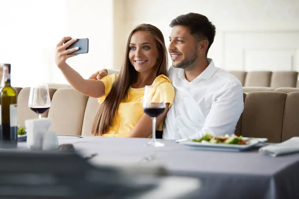 Couple In Restaurant. Couple Taking Photos On Phone.