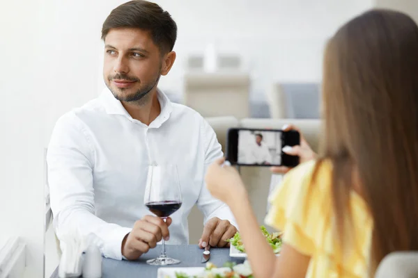 Jantar romântico. Mulher tirando fotos de homem no restaurante — Fotografia de Stock