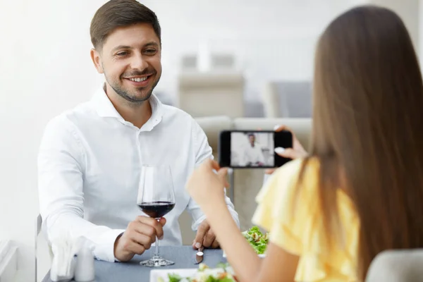 Jantar romântico. Mulher tirando fotos de homem no restaurante — Fotografia de Stock
