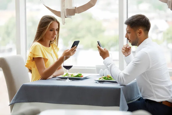 Проблемы связи. Мужчина и женщина с телефонами на свидании — стоковое фото