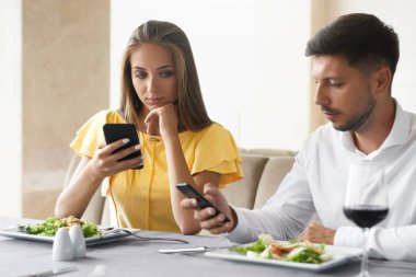 Telefonunu restoranda akşam yemeği kullanarak çift.