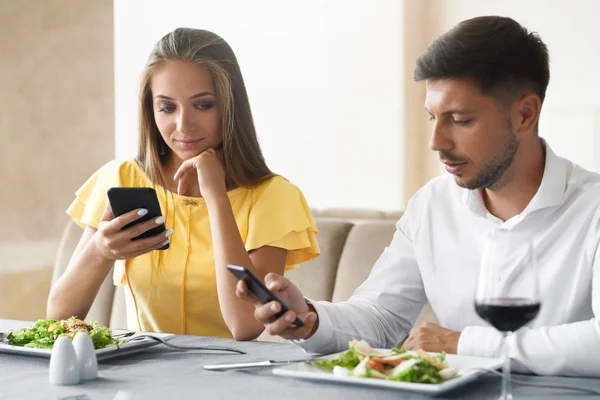 Пара с помощью телефонов на ужин в ресторане . — стоковое фото