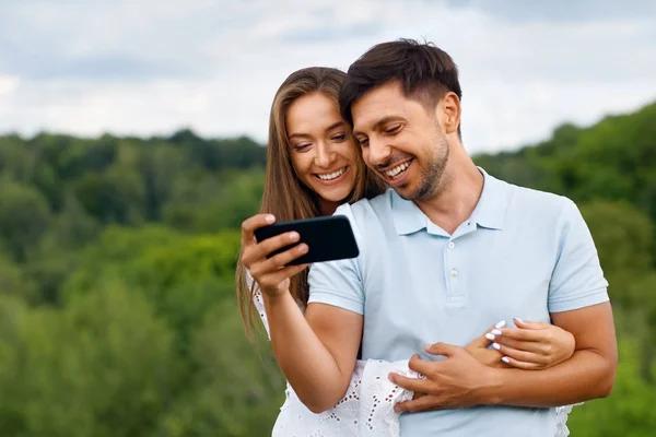 Pareja enamorada. Hombre y mujer mirando el teléfono en la naturaleza . — Foto de Stock