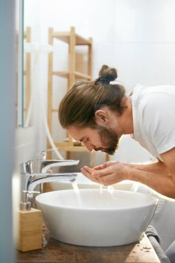 Adam yüz yıkama. Genç erkek yüz banyo temizliği.