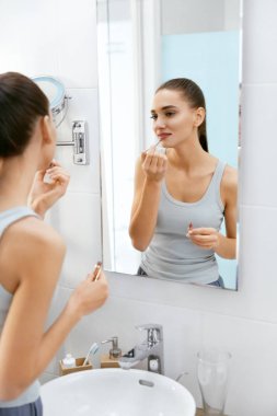 Kadının sabah banyoda makyaj yapması.