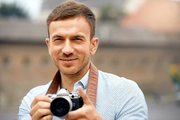 Mężczyzna fotograf fotografowania w aparacie na ulicy — Zdjęcie stockowe