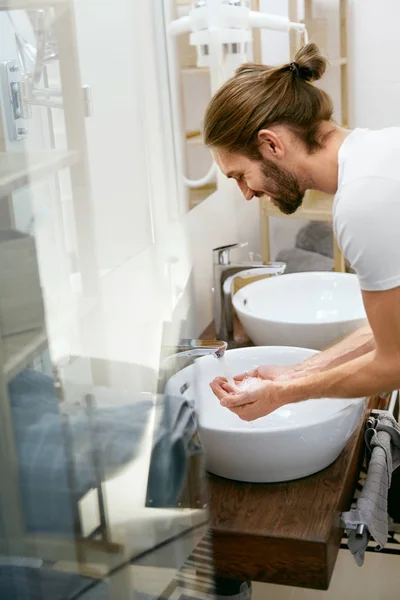 Hombre lavando la cara. Cara de limpieza masculina joven en el baño . —  Fotos de Stock