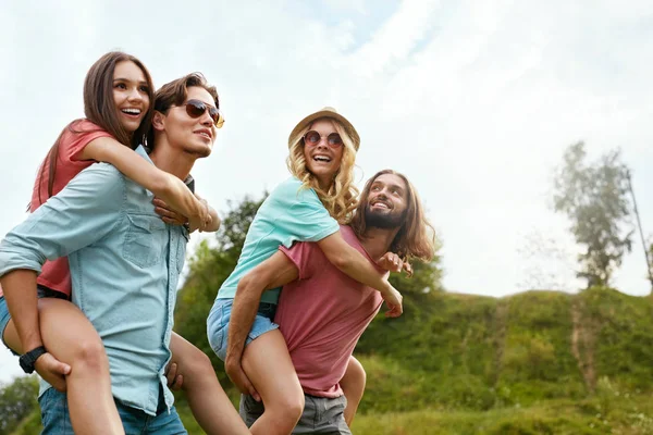 Amigos en fin de semana. Hombres felices llevando mujeres en la naturaleza . — Foto de Stock