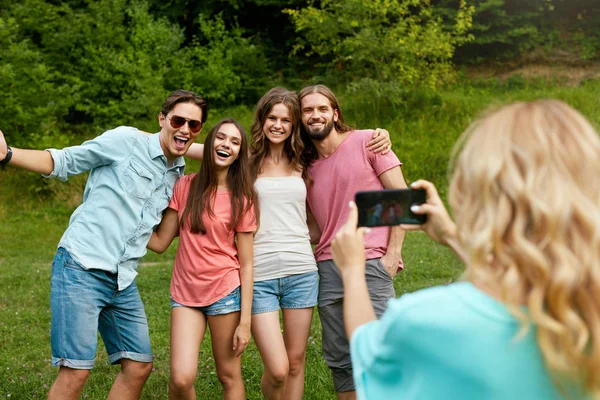 Amigos felices tomando fotos en el teléfono en la naturaleza . — Foto de Stock