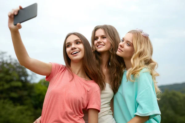 Hermosas chicas tomando fotos en el teléfono en la naturaleza . — Foto de Stock