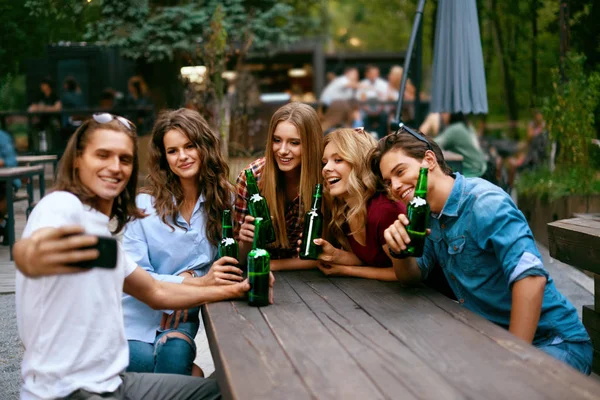 Grupo de amigos bebendo cerveja e tirando fotos no telefone — Fotografia de Stock