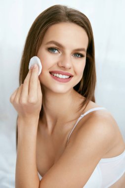 Woman Cleaning Face With White Pad clipart