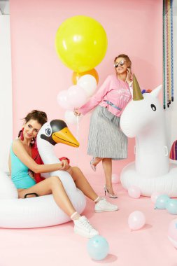 Moda. Havuz yüzen üzerinde eğleniyor renkli giysili kadınlar