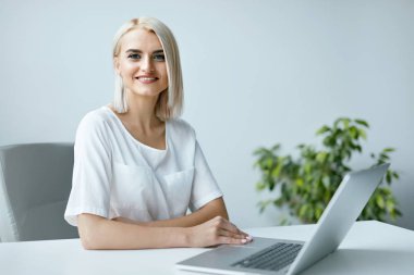 Dizüstü ofiste çalışan genç kadın.